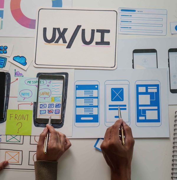 Two designers collaborate on mobile app wireframes, focusing on user interface design and functionality in a creative workspace.